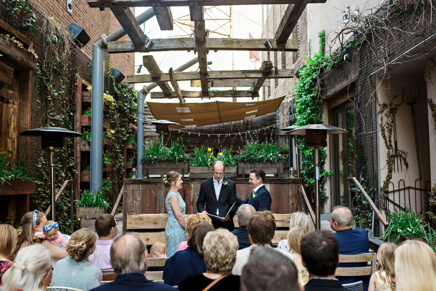 A bride and groom stand in front of their friends and family to say I do.